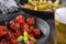 Plate of confit tomatoes  and roasted potatoes with rosemary in iron casserole on dark background