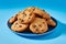 A plate of cookies with chocolate chips on a blue background