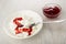 Plate with cottage cheese, sour cream, strawberry jam, spoon, transparent bowl with jam on wooden table