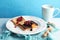 Plate with creative sweet toasts and cup of milk on table