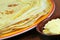 Plate of crepes next to a ramekin of butter in close up