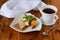 Plate with crispbread, cheese, ham, cherry tomato, cup of coffee on a wooden background. Healthy breakfast. Healthy