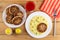 Plate with cutlets, tomato juice, plate with fried cutlet and mashed potato, salt and pepper, fork on napkin on table. Top view