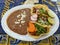 A plate of delicious Al Pastor Tacos with a side of refried beans.