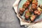 Plate of delicious barbecued meat on gray background, top view.