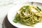 Plate with delicious basil pesto pasta on table