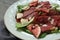 Plate with delicious bresaola salad on grey table, closeup