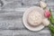 Plate with delicious doughnut with white Crea mIcing, and beautiful Tulip flowers on Rustic grey background with copy space for Te