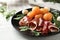 Plate with delicious melon balls, mozzarella and prosciutto on white wooden table, closeup