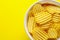 A plate of delicious potato chips fried and salted on a bright yellow background. Copyspace, close-up