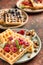 Plate with delicious waffles, berries and nuts on table