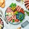 Plate with different kinds of cheese and ham, prosciutto, jamon salami, and snacks. Antipasto Dinner or aperitif party concept.