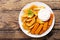 Plate of fish sticks with fried potatoes on a wooden table