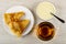 Plate with folded thin russian pancakes, spoon in bowl with condensed milk, cup with hot tea on wooden table. Top view