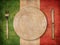 Plate, fork and knife on grunge italian flag background