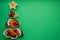 Plate in the form of a Christmas tree with vegetables, fruits, mushrooms and berries.Green background. The concept of vegetarian