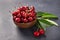 Plate with fresh cherries with green leaves. Black background