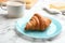 Plate of fresh croissant with condensed milk on white marble table. French