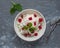 A plate of fresh homemade cottage cheese with sour cream and dried cherries and mint leaves for a light breakfast. Teaspoons lie