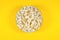 Plate of fresh popcorn on a yellow background. Cinema and entertainment concept. Top view