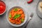 Plate of freshly cooked Penne all`Arrabbiata pasta and ingredients top view