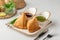 Plate of freshly-fried samosas accompanied by two dipping sauces