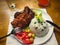 A plate of Fried chicken with rice and vegetables, fork, knife, hot sauce, napkin, slice of lemon and glass of water.