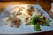 A plate full of dumplings topped with cracklings. Sunlight illuminating the dish. Traditional Polish dish