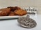 A plate full of Hannukah potato latkes fritters with a silver dreidel on a white table with a silver chanukiah in the background