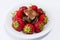 Plate full of tasty juicy strawberries and chocolate isolated on black background. Temptaion dieting summer slimming red berry bea