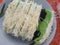 a plate of green and black steamed cakes topped with delicious