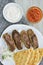 Plate with grilled kebabs ,pita bread and chopped onion and yogurt and tomato sauce in bowls