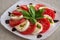 Plate of healthy classic delicious caprese salad with tomatoes and mozzarella cheese with fresh basil leaves on light linen