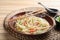 Plate of hot noodles with broth, vegetables and chopsticks