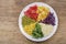 Plate of ingredients for salad : couscous, rocket salad, tomatoes, cabbage,  pepper, corn and green pea, top view