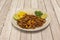 Plate of ingredients of tacos al pastor. Chopped pineapple, gisada meat, chopped onion and coriander with two pieces of lime on a