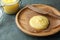 Plate and knife with Ghee butter on light blue wooden table, closeup