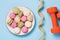 Plate with macaroons, dumbbells and measuring tape on a blue background. Concept on the topic of a healthy lifestyle