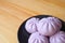 Plate of many purple sweet potato steamed buns on wooden table