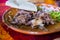 Plate of Mexican chopped lamb meat on colorful tablecloth