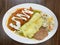 plate with mexican food, poblano pepper with red sauce, enchiladas with cheese gratin, rice and beans