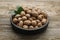 Plate with nutmeg seeds and green leaves on wooden table