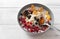 Plate of oatmeal with fruit, porridge, dried apricots, raisins, pomegranates, Mandarin slices on a white background, healthy