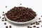 A plate overflowing with coffee beans on a white background.