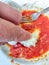 Plate of pasta just finished with hand cleaning the remaining tomato with a piece of bread.