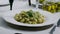 A plate of pasta with pesto sauce and a green vegetable on top
