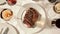 A plate of perfectly grilled steak sits in the center of a table its caramelized edges and juicy interior tantalizingly