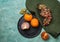 Plate with persimmons and ripe grapes on color table