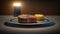 a plate with a piece of meat and a small cupcake with a lit candle in the background on a table with a table cloth. generative