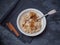 A plate of porridge with a sprinkling of cinnamon and banana circles. Shot close up on a dark wooden background